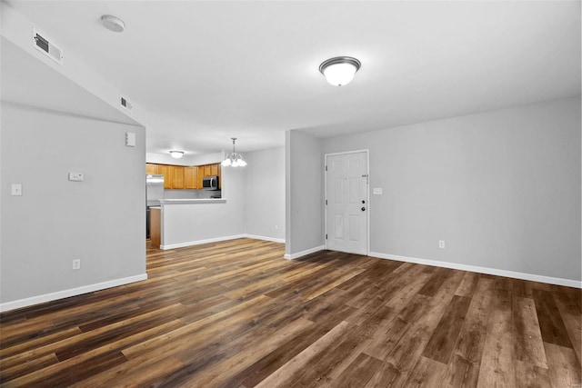 unfurnished living room with dark hardwood / wood-style flooring and an inviting chandelier