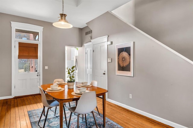 dining room with light wood finished floors, visible vents, and baseboards