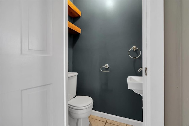 bathroom with toilet, baseboards, and tile patterned floors