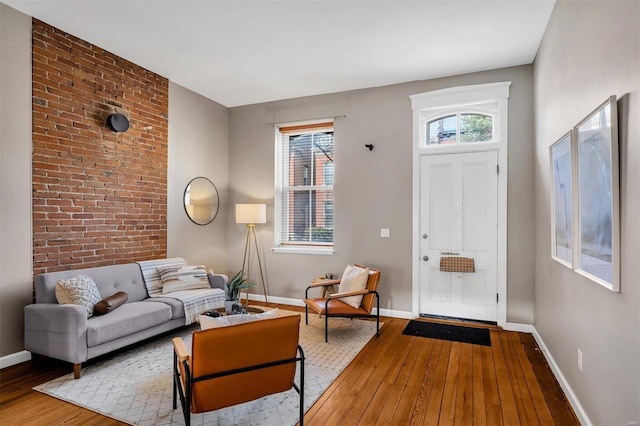 interior space with brick wall, baseboards, and hardwood / wood-style floors