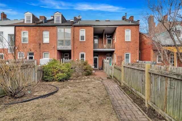 back of house featuring fence and brick siding