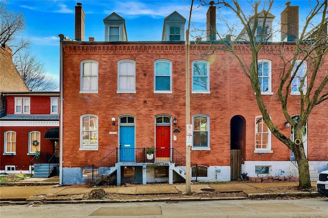 view of front facade featuring brick siding and a chimney