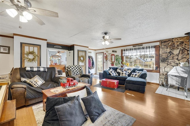 living room with ceiling fan, ornamental molding, a textured ceiling, and light hardwood / wood-style floors