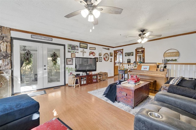 living room featuring french doors, crown molding, light hardwood / wood-style flooring, a textured ceiling, and plenty of natural light