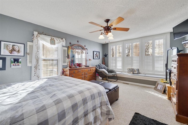 bedroom with multiple windows, carpet floors, a textured ceiling, and ceiling fan