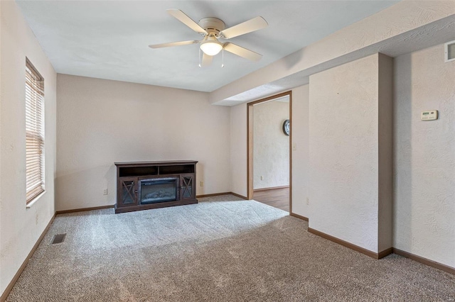 unfurnished living room with ceiling fan and carpet