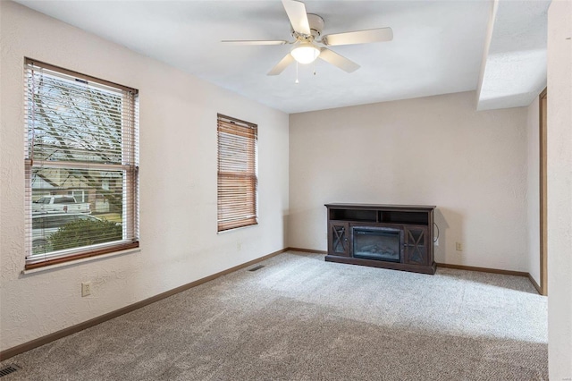 unfurnished living room featuring ceiling fan and carpet flooring