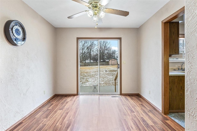 unfurnished room with sink, hardwood / wood-style floors, and ceiling fan