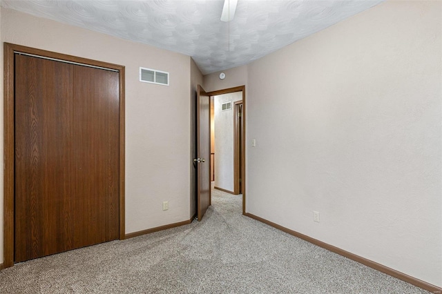 unfurnished bedroom with light colored carpet, ceiling fan, and a closet