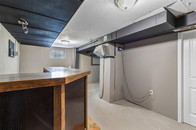 basement with bar and a textured ceiling