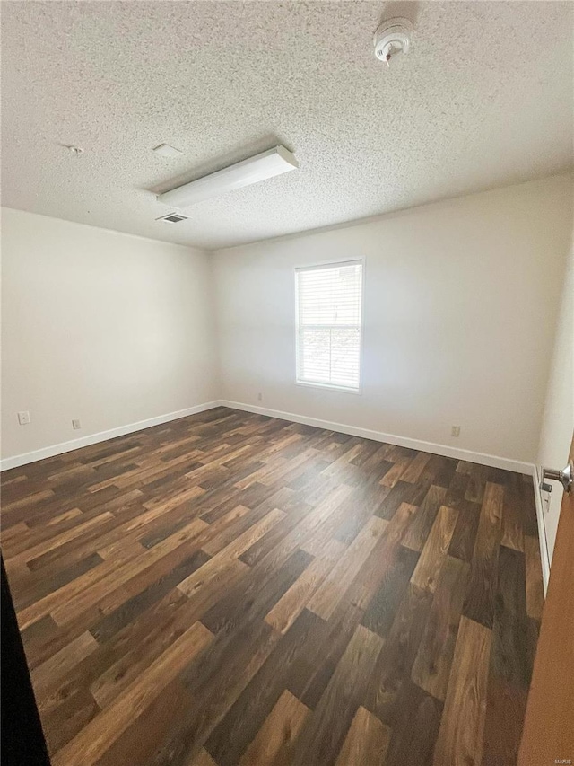 unfurnished room featuring dark hardwood / wood-style floors and a textured ceiling