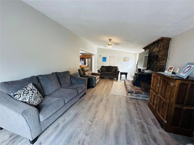 living room featuring lofted ceiling, light hardwood / wood-style flooring, and ceiling fan