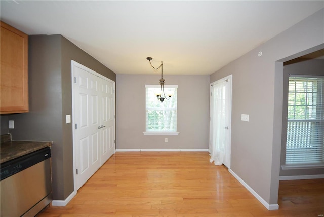 unfurnished dining area featuring a chandelier, a wealth of natural light, and light wood-type flooring