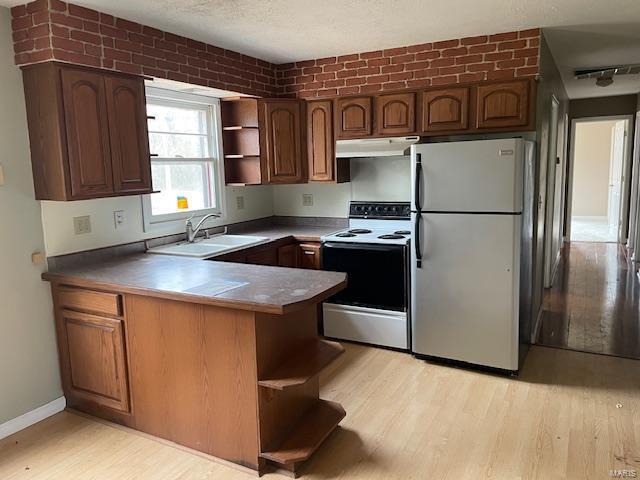 kitchen with white electric range oven, sink, light wood-type flooring, stainless steel refrigerator, and kitchen peninsula