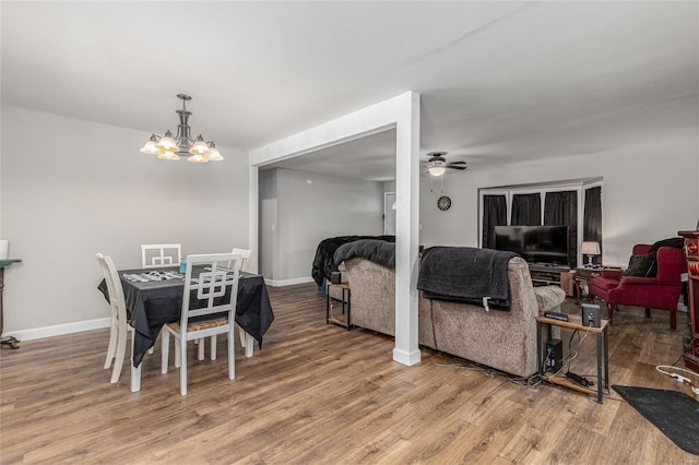 dining space with wood-type flooring and ceiling fan with notable chandelier