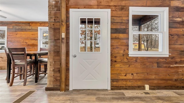 doorway to outside with wood-type flooring and wooden walls