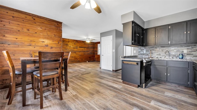 kitchen with sink, black electric range, light wood-type flooring, ceiling fan, and backsplash