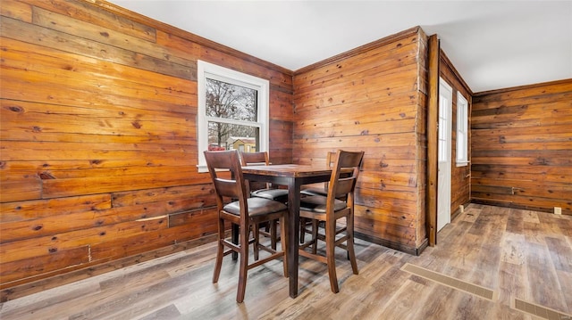 dining area featuring hardwood / wood-style flooring and wooden walls