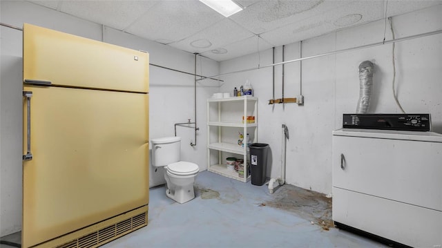 bathroom featuring concrete flooring, washer / dryer, a paneled ceiling, and toilet