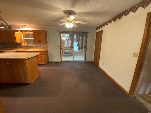 kitchen featuring sink, hanging light fixtures, a textured ceiling, dark carpet, and decorative backsplash