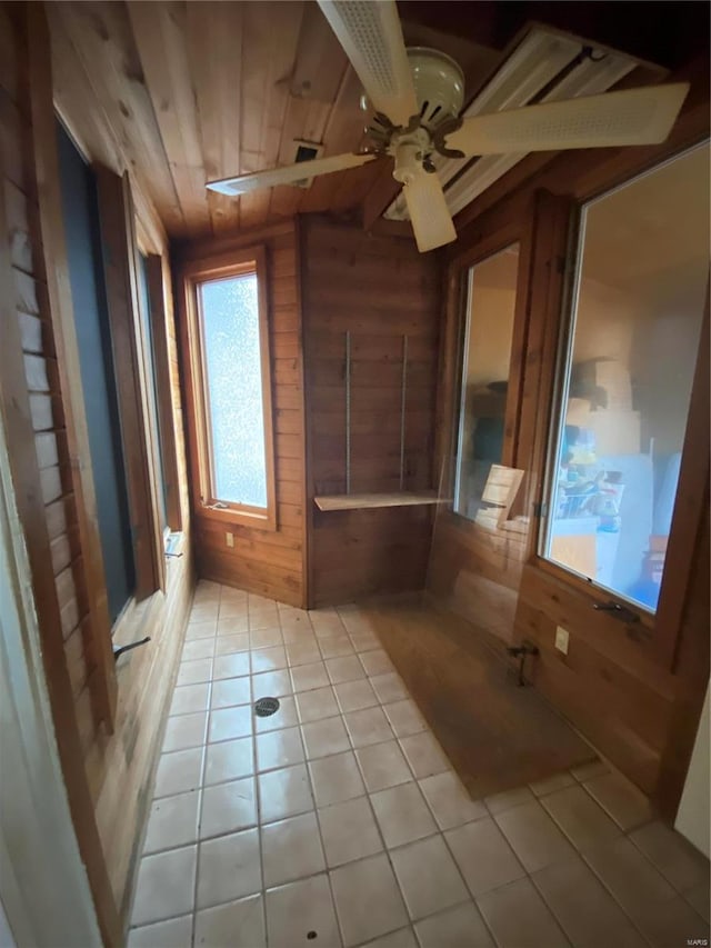 tiled spare room with wood ceiling, ceiling fan, and wooden walls