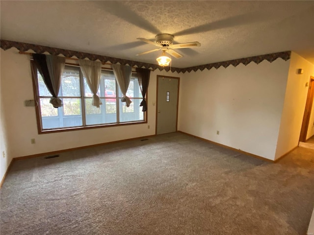 carpeted empty room with ceiling fan and a textured ceiling