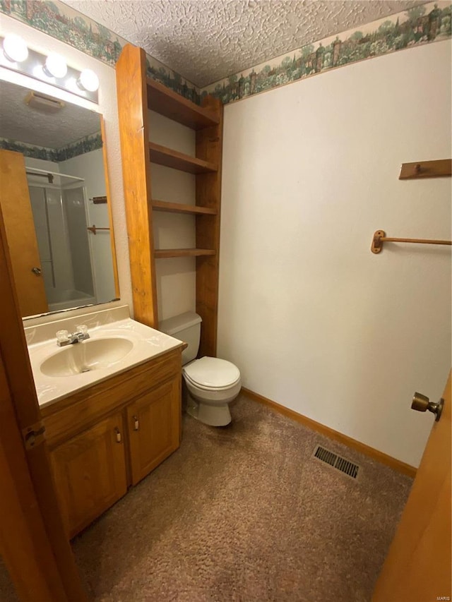 bathroom featuring vanity, toilet, a textured ceiling, and walk in shower