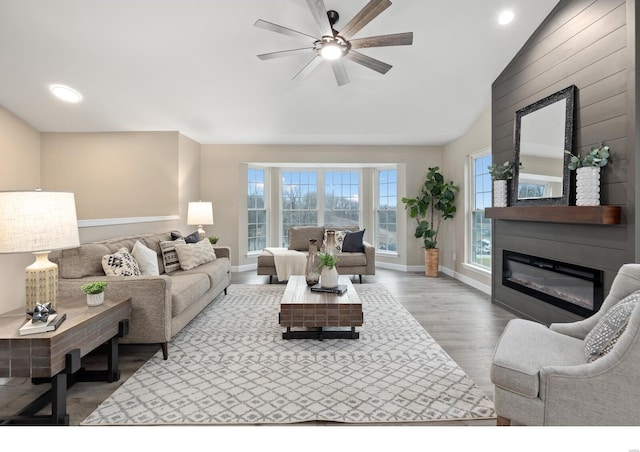 living room with a fireplace, wood-type flooring, ceiling fan, and vaulted ceiling