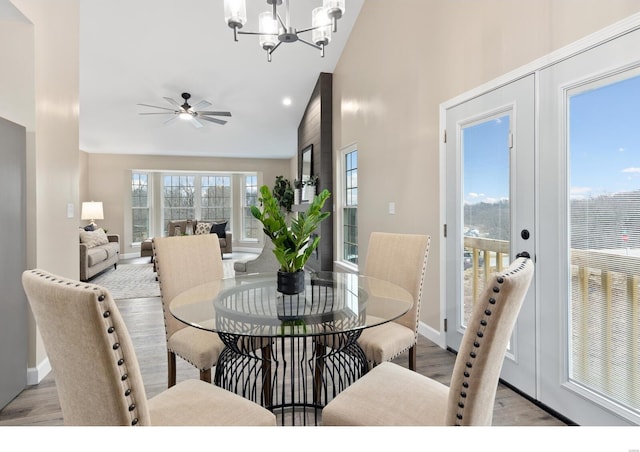 dining room featuring ceiling fan with notable chandelier, high vaulted ceiling, french doors, and light wood-type flooring