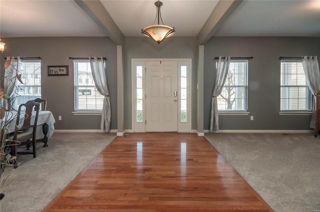 foyer with beam ceiling and carpet