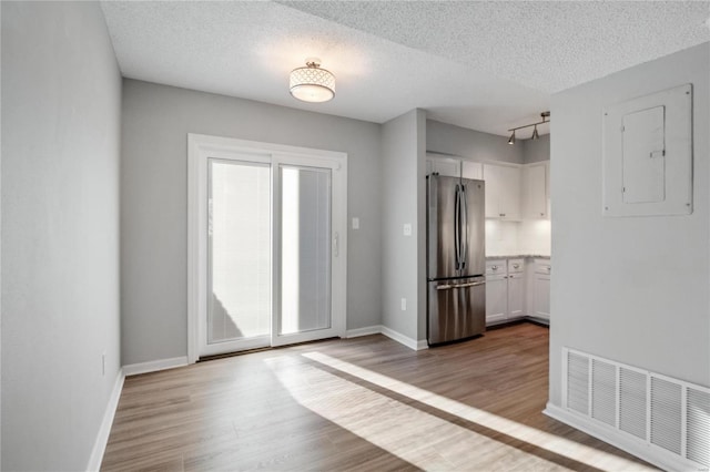 spare room featuring light hardwood / wood-style flooring, electric panel, and a textured ceiling