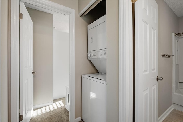 clothes washing area with light colored carpet and stacked washer / dryer