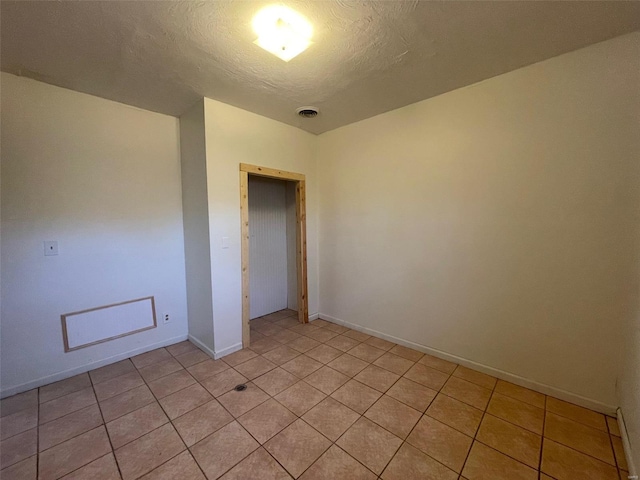 empty room featuring light tile patterned flooring and a textured ceiling