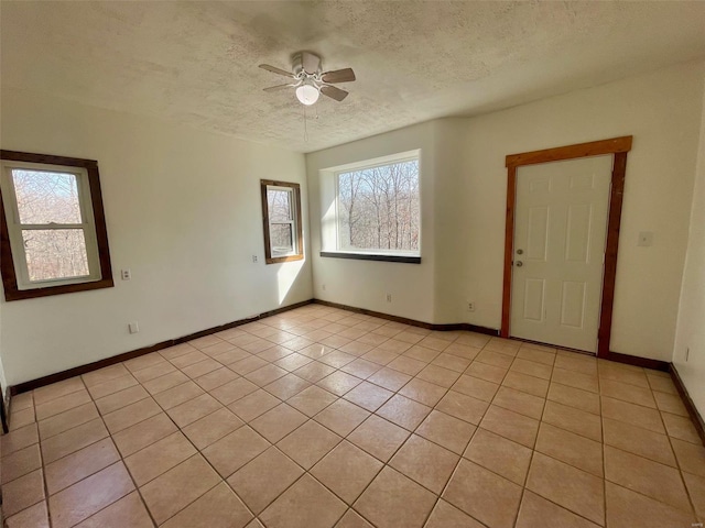 tiled empty room with ceiling fan and a textured ceiling