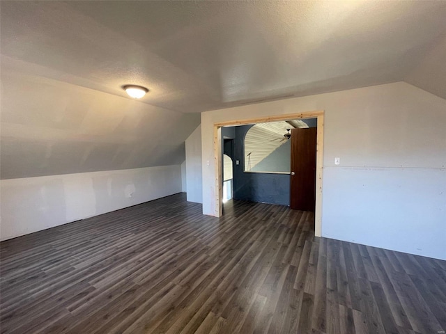 bonus room with dark wood-type flooring, vaulted ceiling, and a textured ceiling