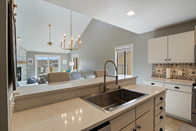 kitchen with a sink, open floor plan, a fireplace, decorative backsplash, and vaulted ceiling