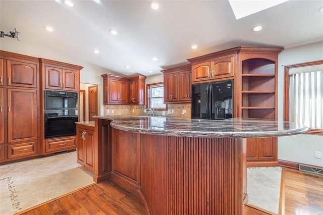 kitchen with a kitchen island, light hardwood / wood-style floors, black appliances, and lofted ceiling