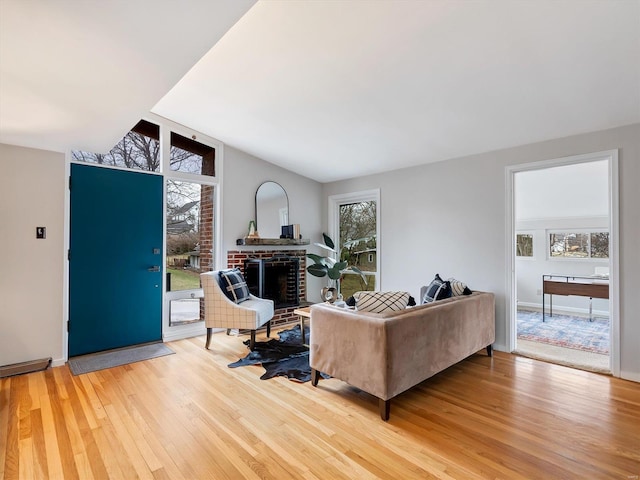 living room with hardwood / wood-style flooring, lofted ceiling, and a fireplace