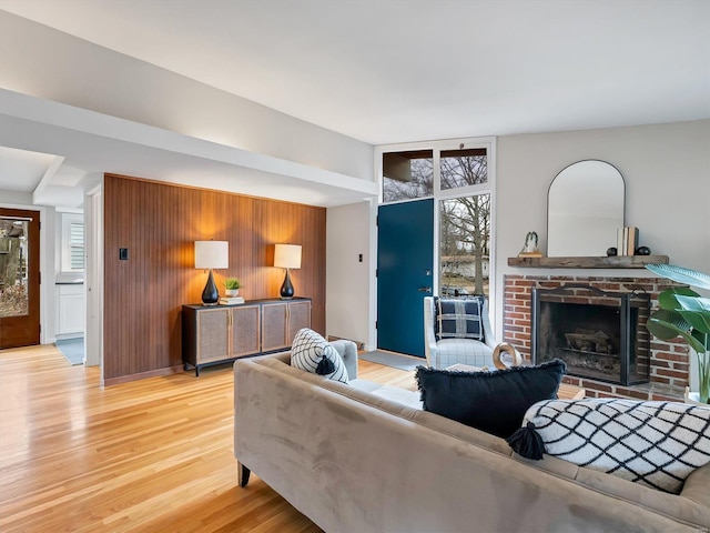 living room featuring wood walls, a fireplace, a wall of windows, and light hardwood / wood-style flooring