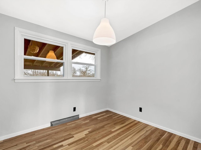 unfurnished room with a baseboard radiator and wood-type flooring