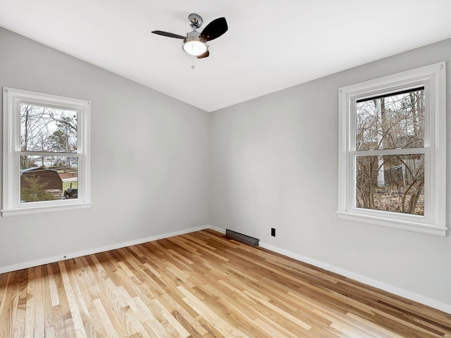 spare room featuring a healthy amount of sunlight, ceiling fan, and light hardwood / wood-style flooring