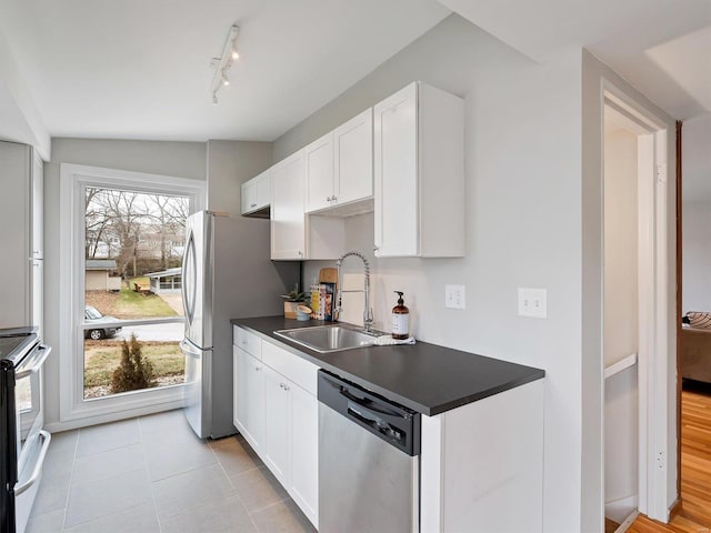 kitchen featuring white cabinetry, sink, light tile patterned floors, and appliances with stainless steel finishes