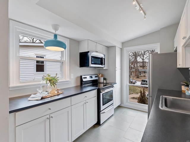 kitchen with white cabinetry, stainless steel appliances, decorative light fixtures, and sink