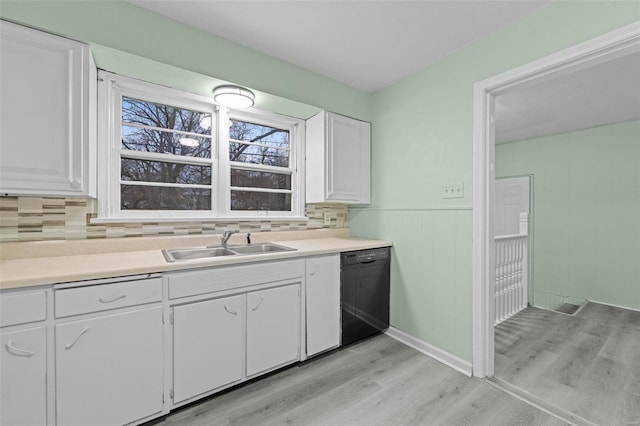 kitchen with white cabinetry, sink, light hardwood / wood-style floors, and black dishwasher