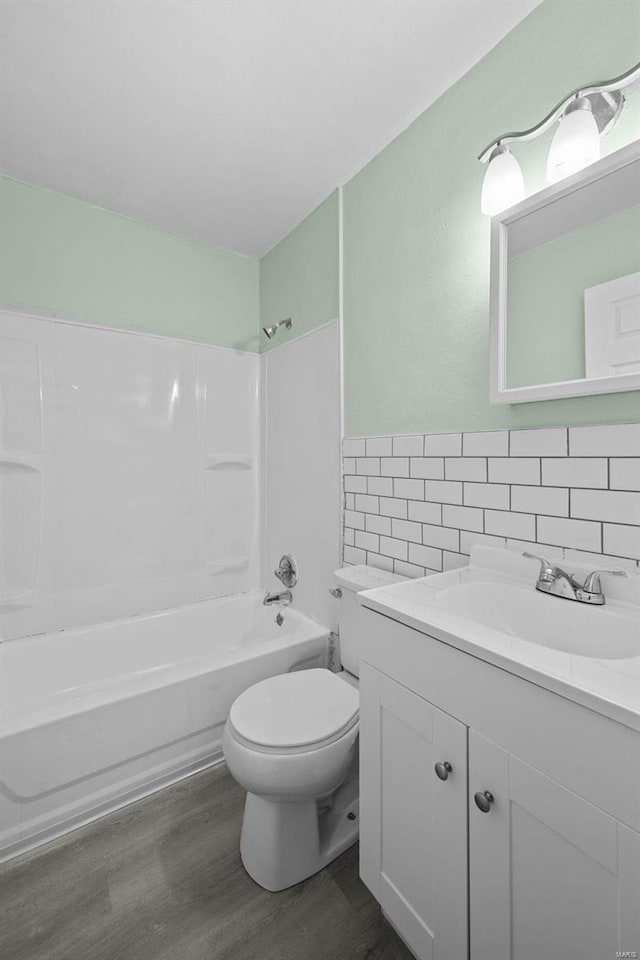 full bathroom featuring tile walls, hardwood / wood-style floors, vanity, bathtub / shower combination, and toilet