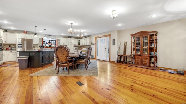 dining room with light hardwood / wood-style flooring and a chandelier