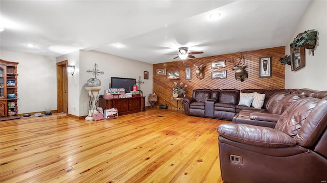 living room with ceiling fan, wooden walls, and light hardwood / wood-style flooring