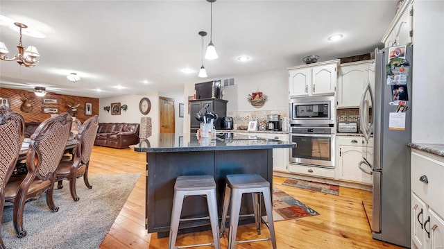 kitchen featuring white cabinetry, decorative light fixtures, light wood-type flooring, stainless steel appliances, and decorative backsplash