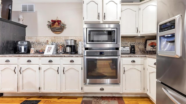 kitchen with white cabinetry, appliances with stainless steel finishes, backsplash, and light wood-type flooring