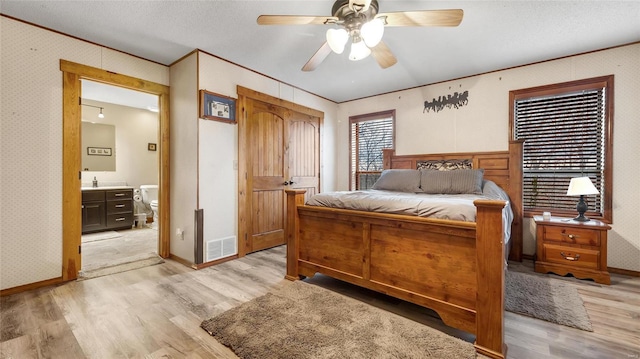 bedroom featuring connected bathroom, light hardwood / wood-style flooring, a textured ceiling, ornamental molding, and ceiling fan